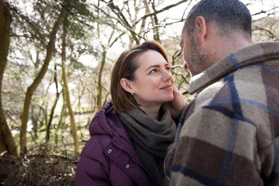 a man and woman are looking at each other in the woods