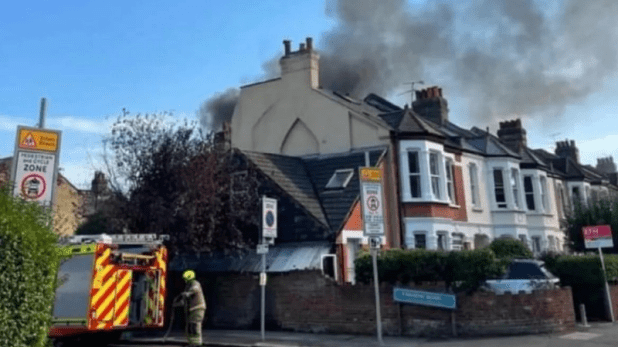 a fire truck is parked in front of a row of houses with smoke coming out of the chimneys