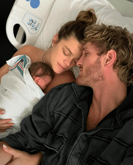 a man and woman laying in a hospital bed holding a newborn baby