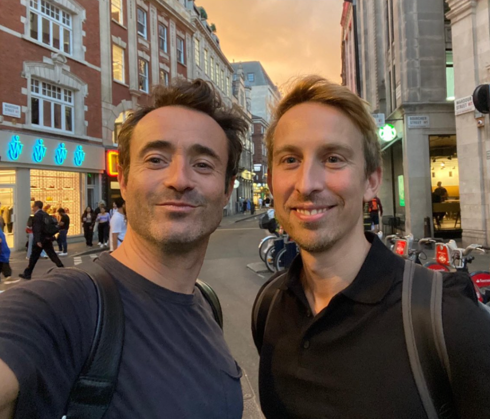 two men are posing for a picture in front of a starbucks