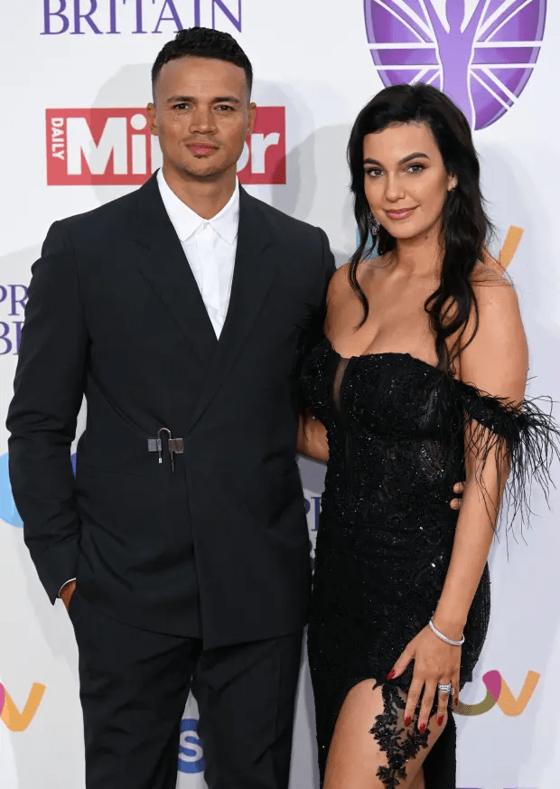 a man and a woman pose for a photo in front of a daily mirror sign