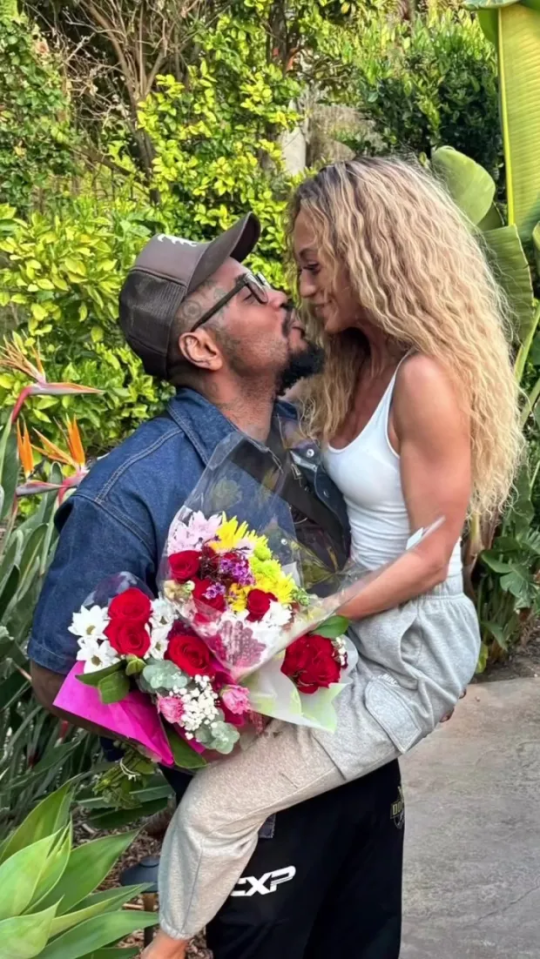 a man is kissing a woman who is holding a bouquet of flowers .