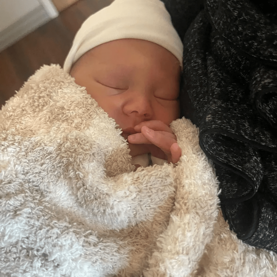 a newborn baby is wrapped in a white blanket and wearing a white hat