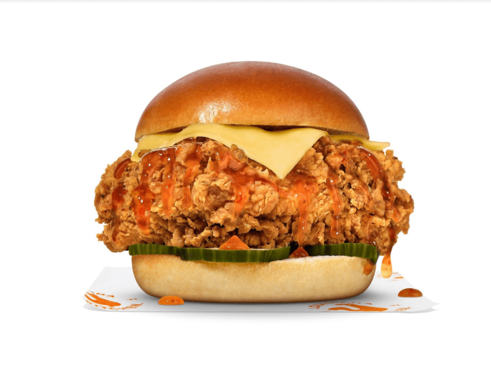 a fried chicken sandwich with cheese and pickles on a bun