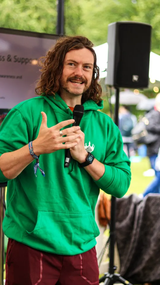 a man in a green hoodie is holding a microphone