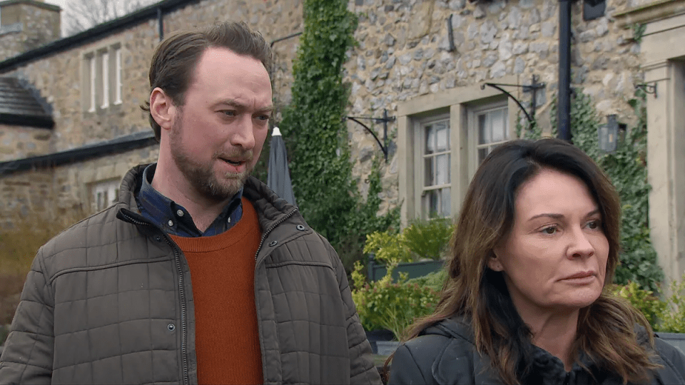 a man and a woman standing in front of a stone building