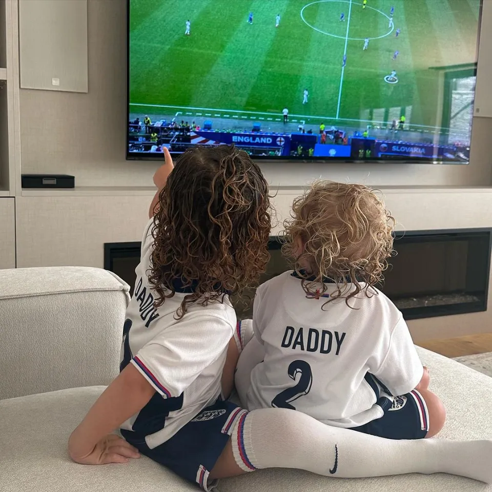 two young boys wearing daddy jerseys watch a soccer game