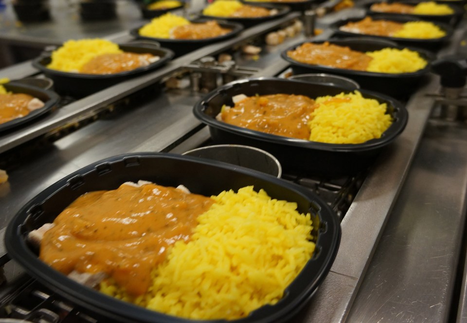 a tray of food with yellow rice and sauce on a conveyor belt