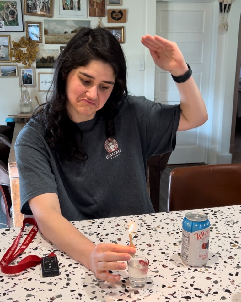 a woman lighting a candle with a can of water next to her