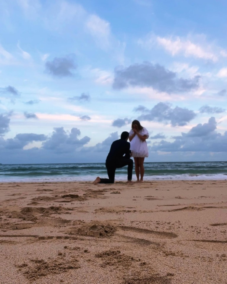 a man kneels down to propose to a woman on the beach