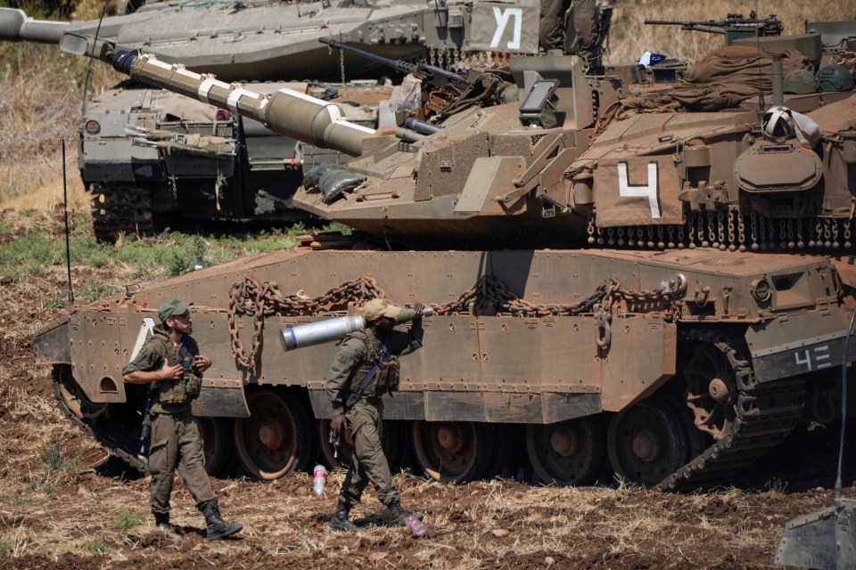 An Israeli soldier carries a shell next to a tank in northern Israel