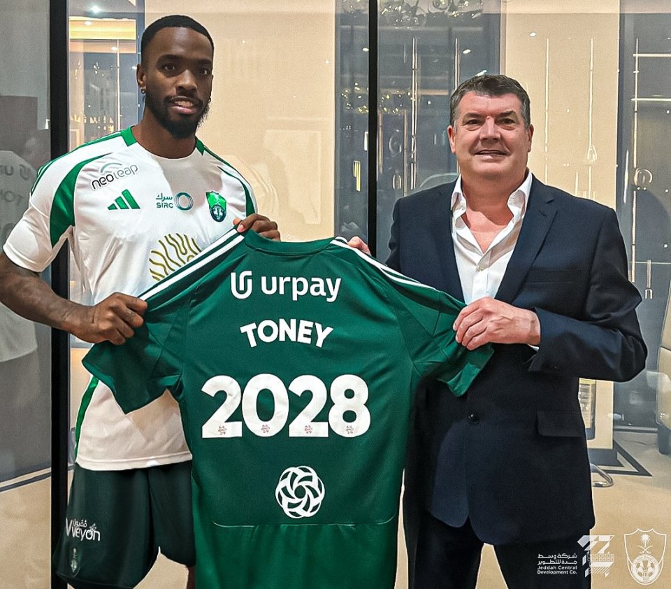 a man in a suit holds up a green shirt that says toney 2028