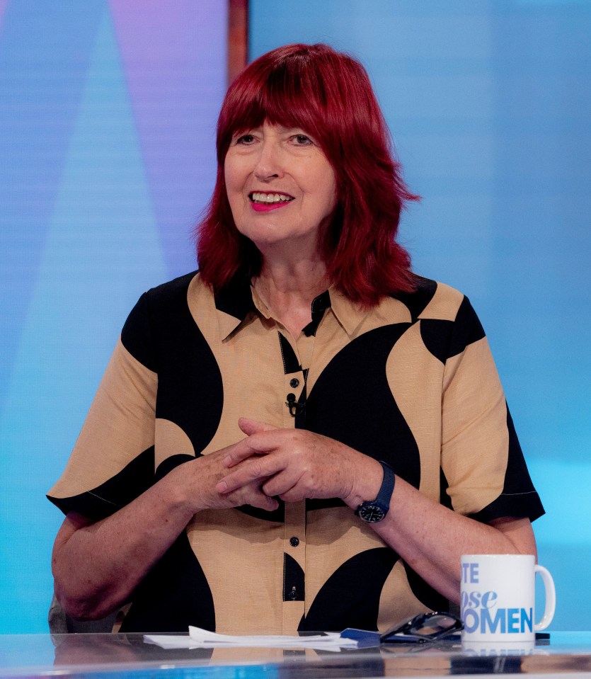 a woman with red hair sits at a table with a mug that says " vote for women "