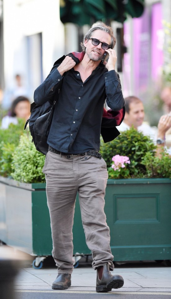 He wore a loosely buttoned-up black shirt as he strolled in the city.