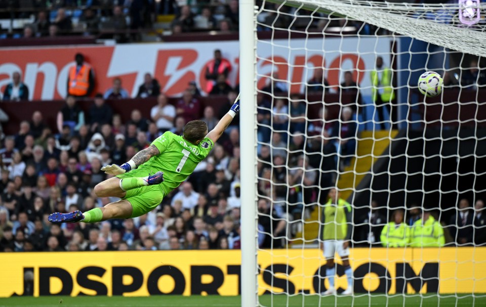 a soccer player jumps to catch a ball in front of an advertisement for jdsports.com