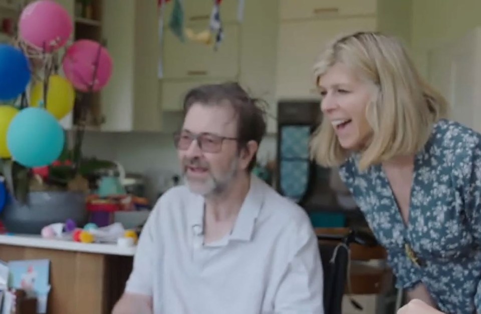 a woman is standing next to a man in a wheelchair .