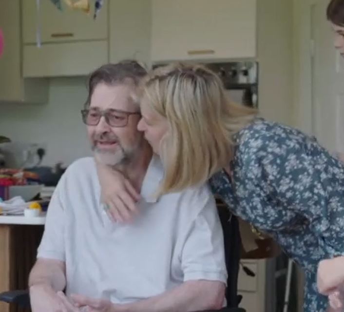 a woman is kissing a man in a wheelchair .