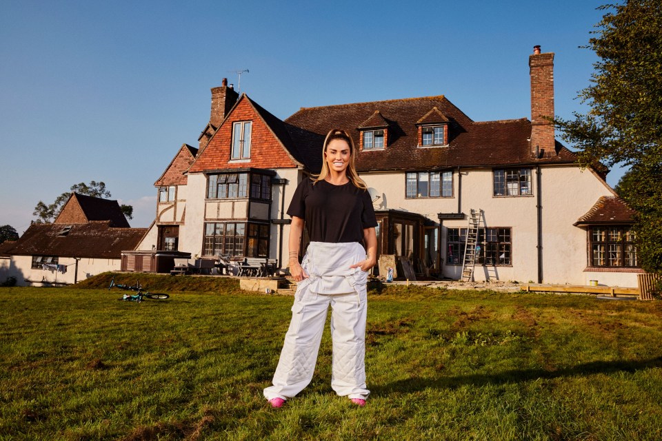 a woman standing in front of a large house with her hands in her pockets