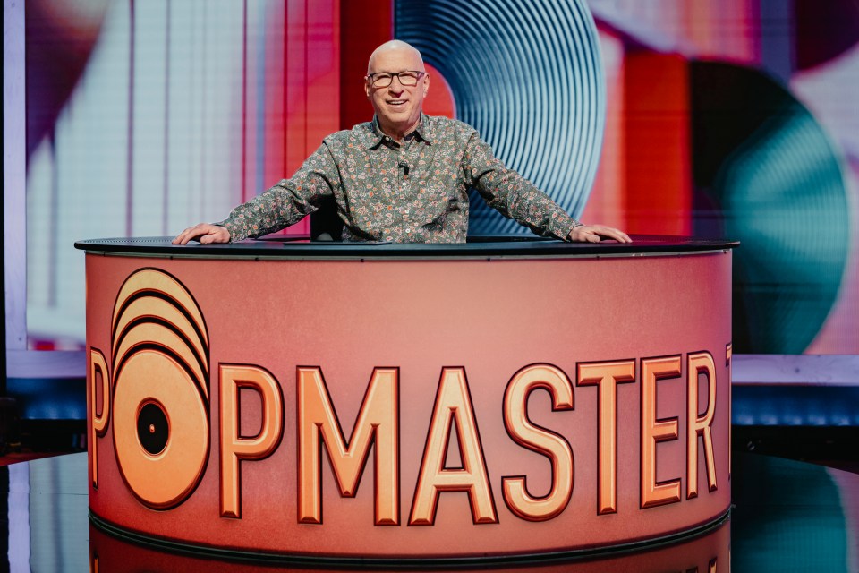 a man stands behind a table that says popmaster