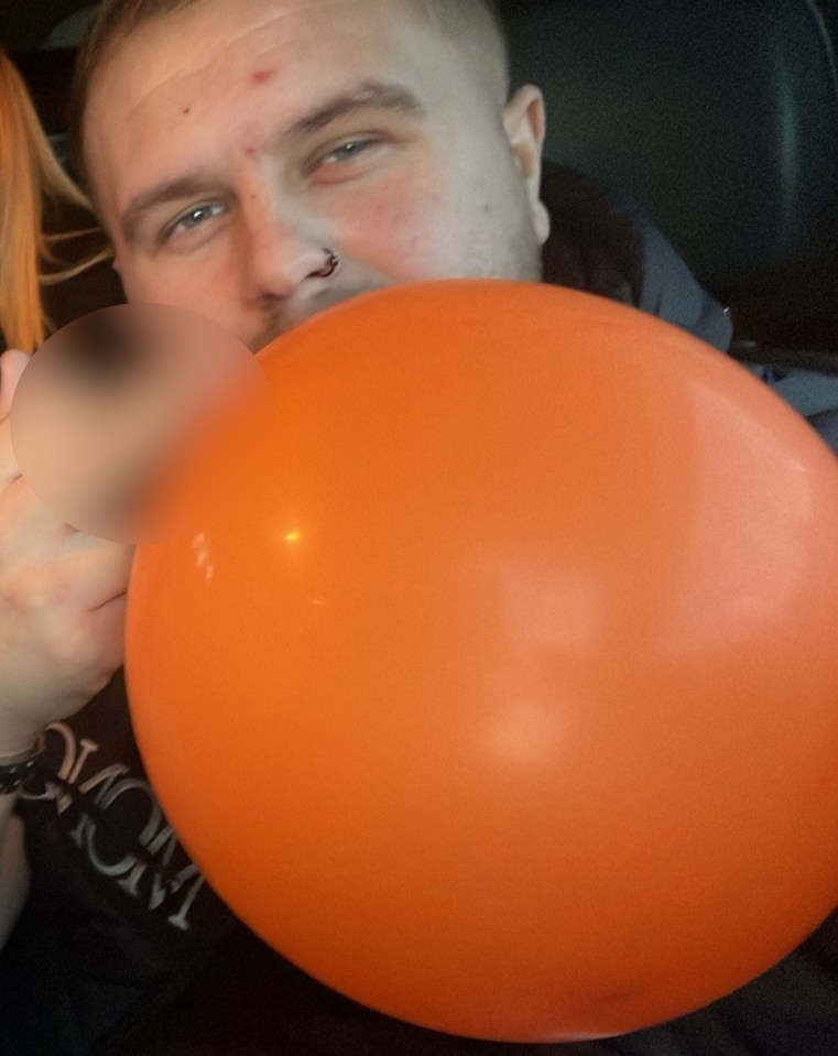 a man blowing up an orange balloon with the word mom on his shirt