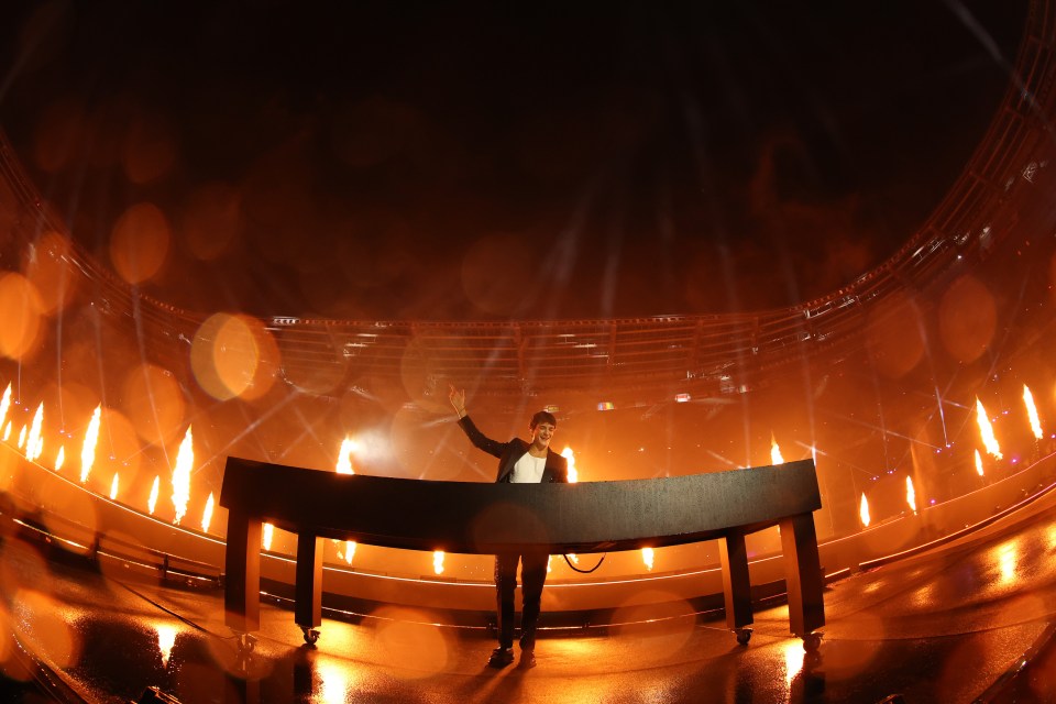 a man stands in front of a stage with flames coming out of it