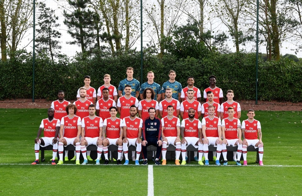 a soccer team poses for a team photo wearing fly emirates jerseys