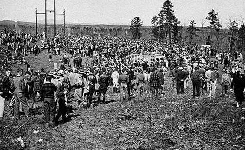 a large group of people are standing in a field .