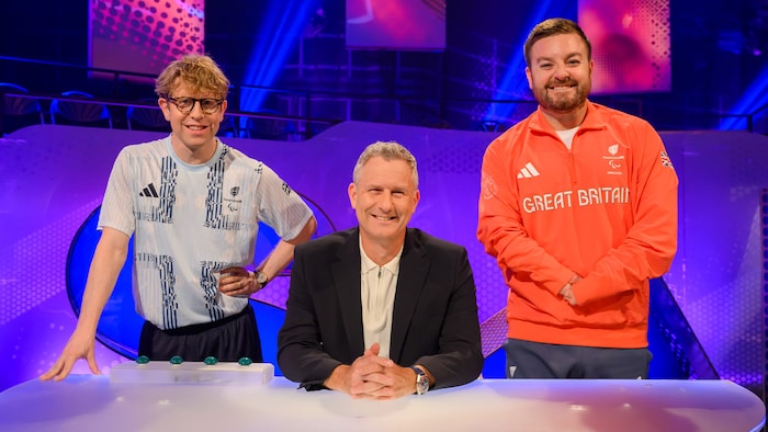 a man wearing a great britain shirt stands next to two other men