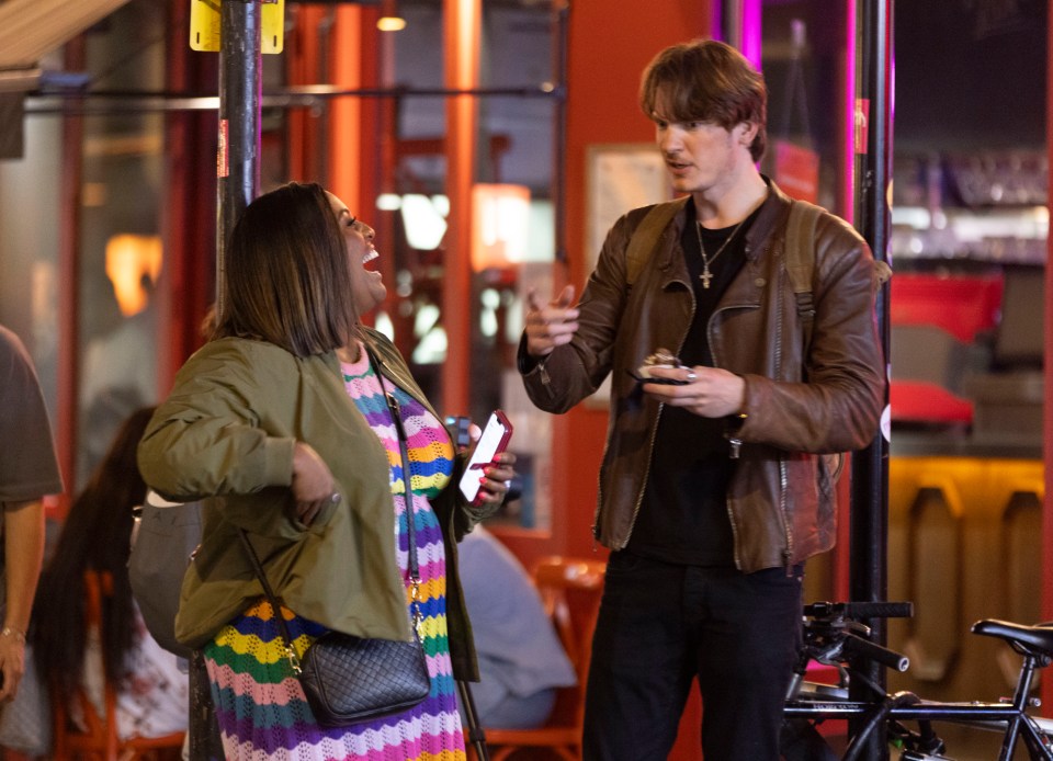 a man in a leather jacket talks to a woman in a rainbow dress