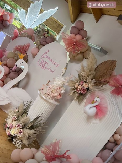 a room decorated with pink balloons and flowers for bonnie 's first birthday