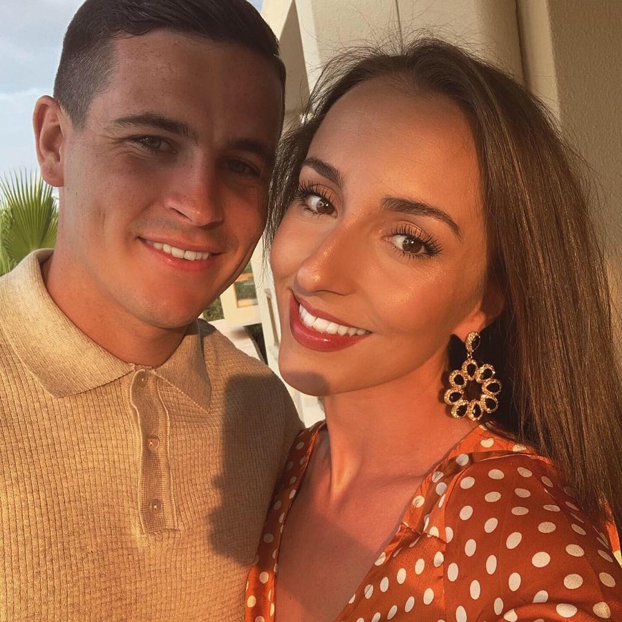 a man and a woman are posing for a picture and the woman is wearing polka dot earrings