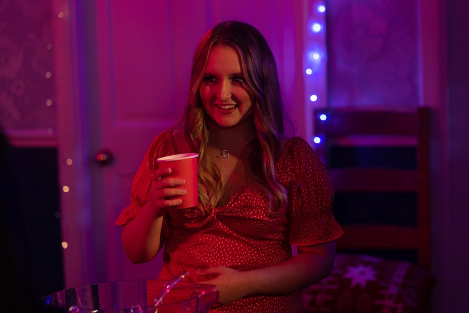 a woman in a red dress is holding a cup and smiling