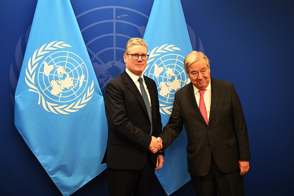 two men shaking hands in front of a united nations flag