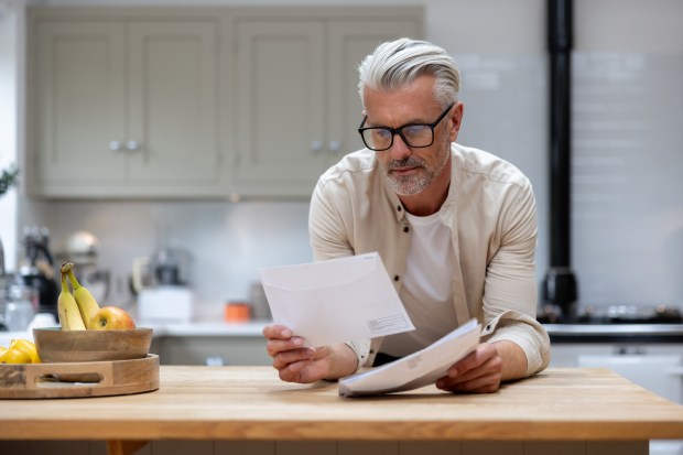 a man sitting at a kitchen counter reading a letter