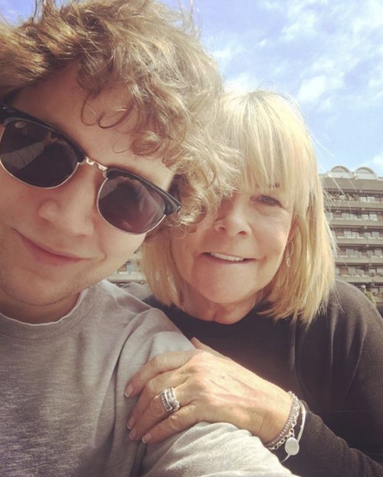 a man wearing sunglasses stands next to an older woman