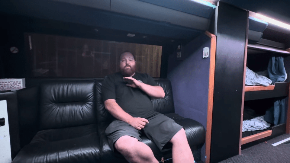 a man with a beard sits on a black leather couch