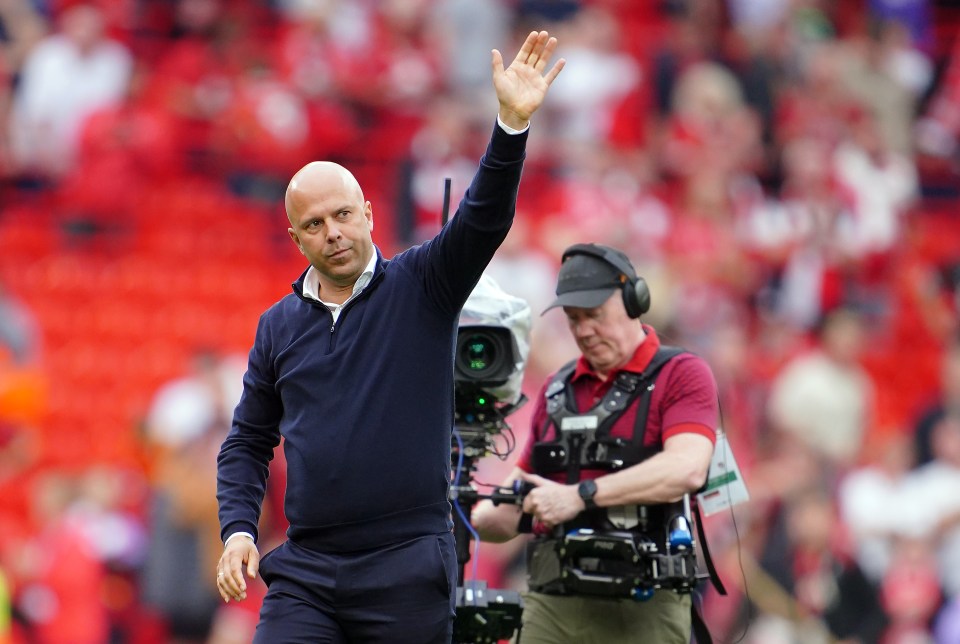 a man in a blue sweater waves to the crowd