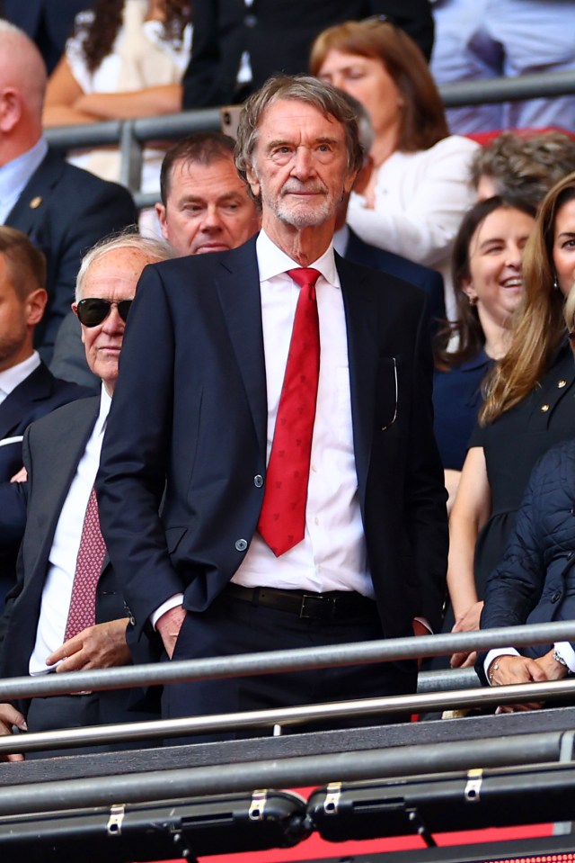 a man in a suit and red tie stands in the stands