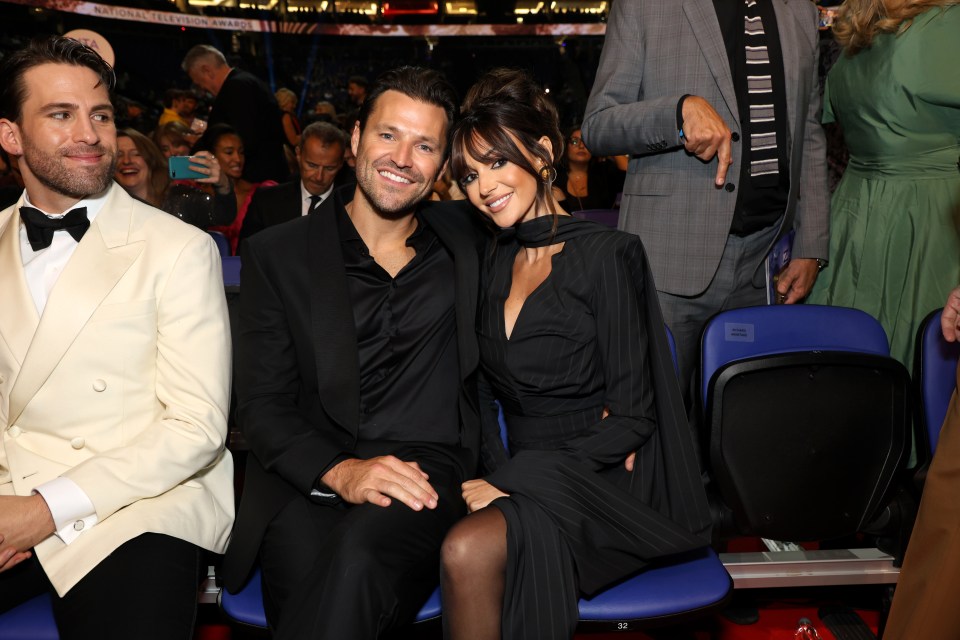 a man in a white suit sits next to a woman in a black dress