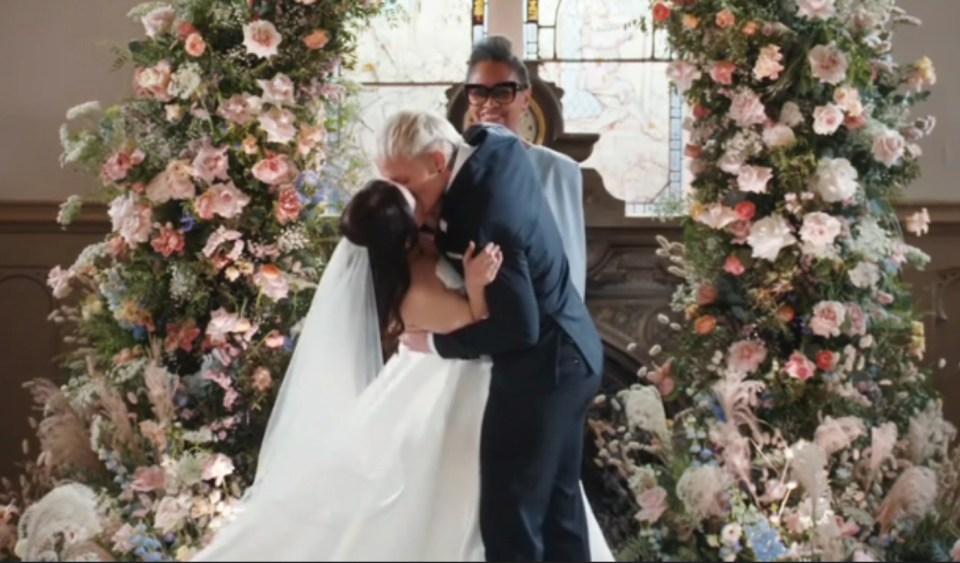 a bride and groom kiss in front of a stained glass window