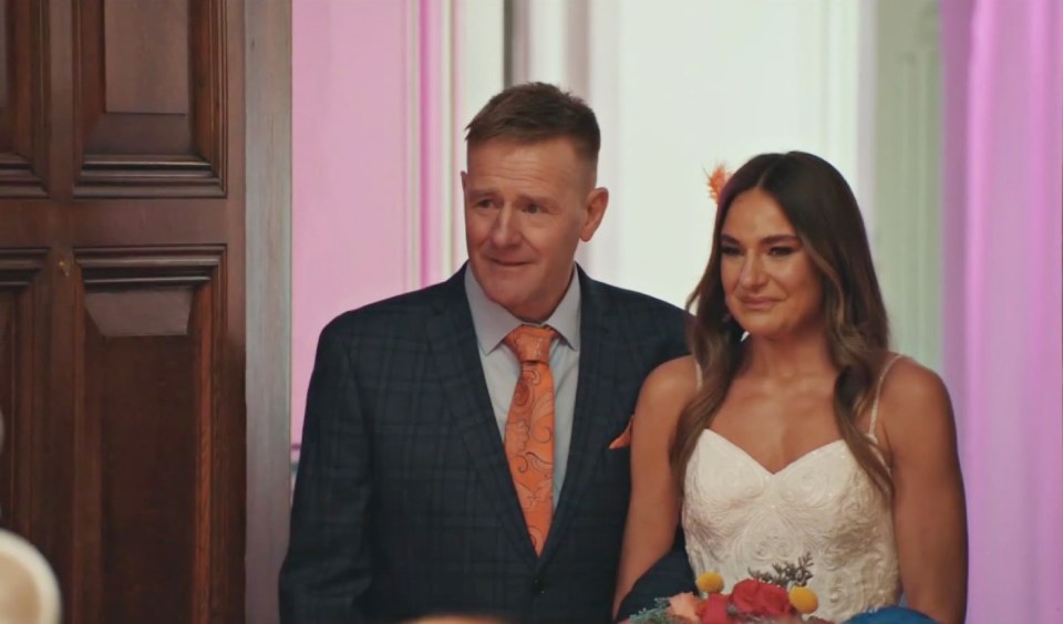 a man in a suit and tie stands next to a woman in a white dress