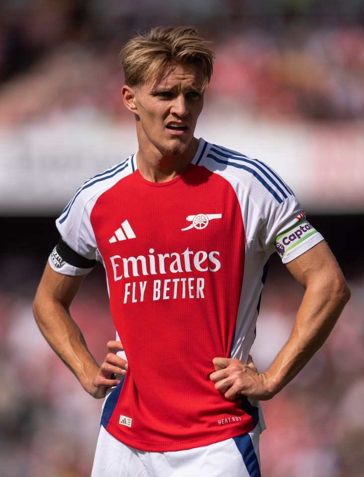 a soccer player wearing a red and white jersey that says emirates fly better