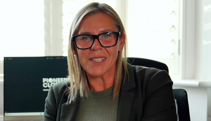 a woman wearing glasses sits in front of a computer screen that says pioneer