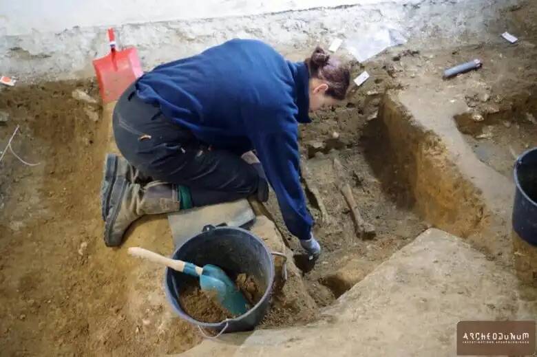 a woman is kneeling in the dirt next to a bucket and shovel ..