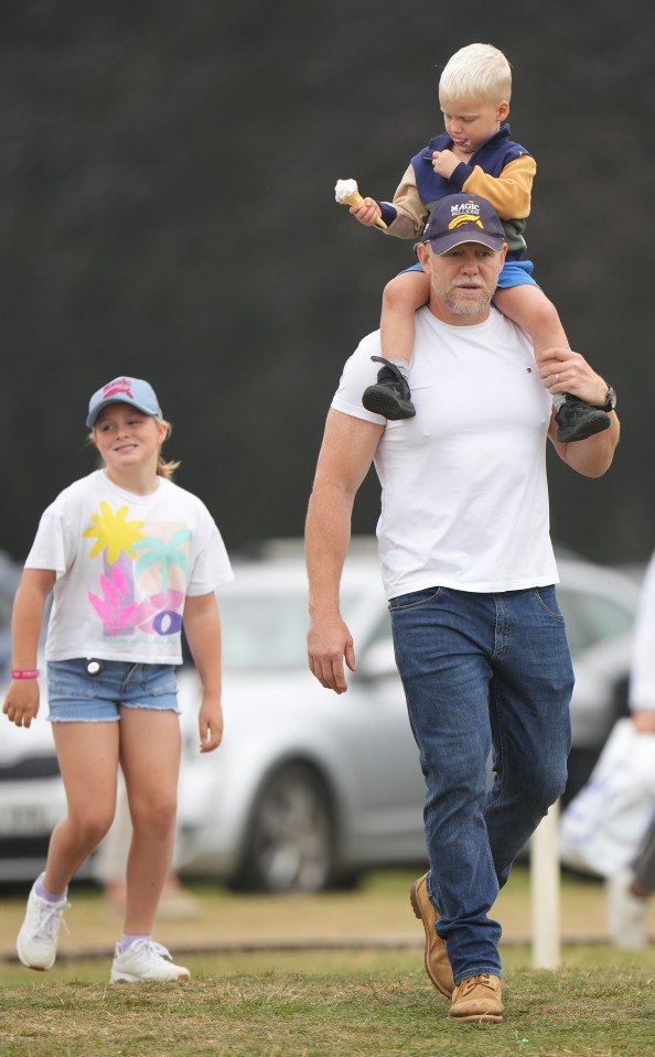 a man carrying a child on his shoulders has a hugo boss hat on