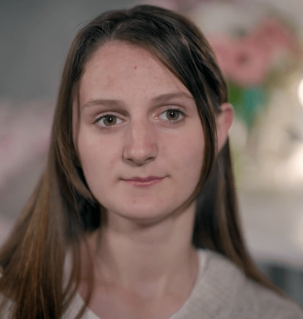 a close up of a woman 's face with flowers in the background