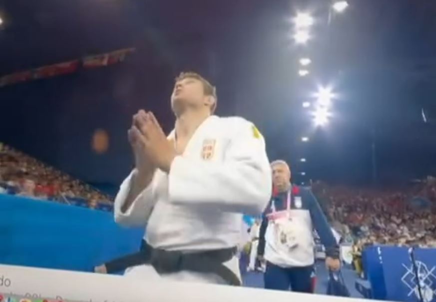 a man in a judo uniform is praying in front of a crowd .