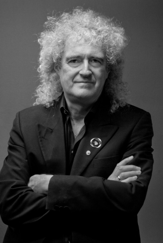 a man with curly hair is wearing a black suit