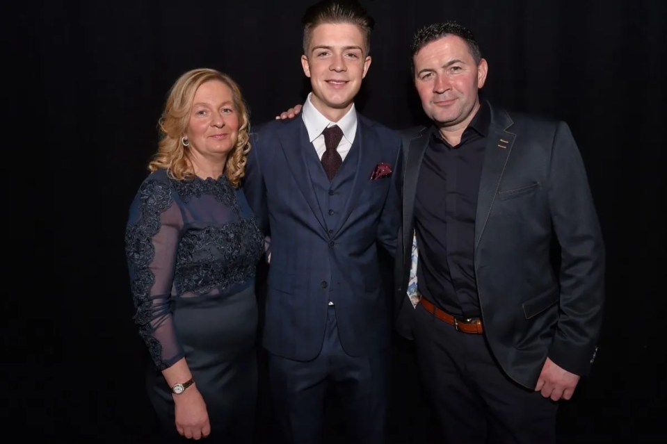 a man and woman pose with a boy in a suit