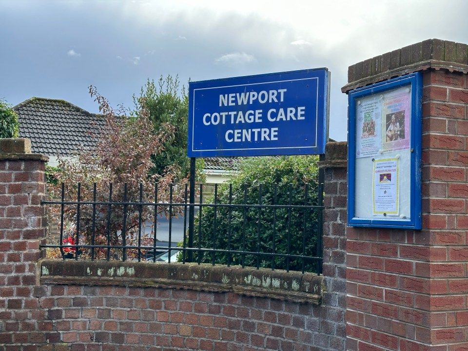 a blue sign on a brick wall says newport cottage care centre